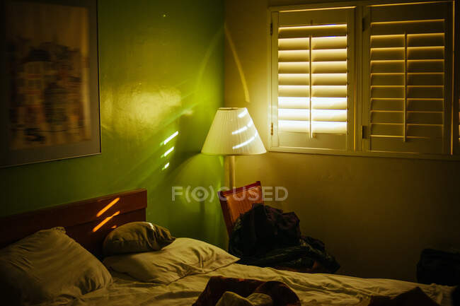Interior of bedroom with blinds on window and scattered things in hotel of Venice beach at sunrise — Stock Photo