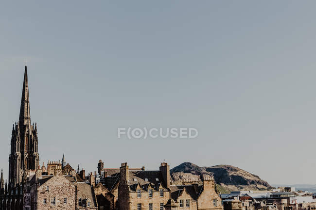 Torre escura velha localizada em meio a casas envelhecidas contra o céu nublado cinza na rua da cidade em Edimburgo, Escócia, Reino Unido — Fotografia de Stock