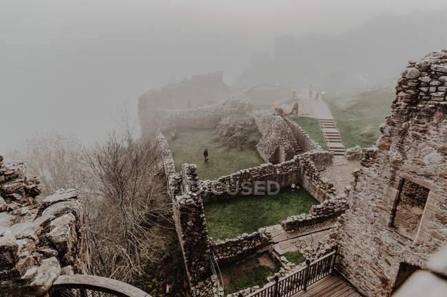 Castelo de pedra velho destruído com nevoeiro com paredes e escadas com torre no dia nublado — Fotografia de Stock