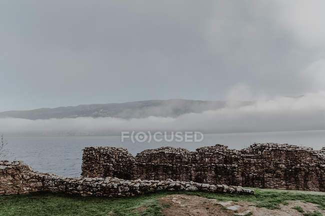 Vista de muros de construção arruinados de montanhas nebulosas e colinas com névoa em turva durante o dia — Fotografia de Stock