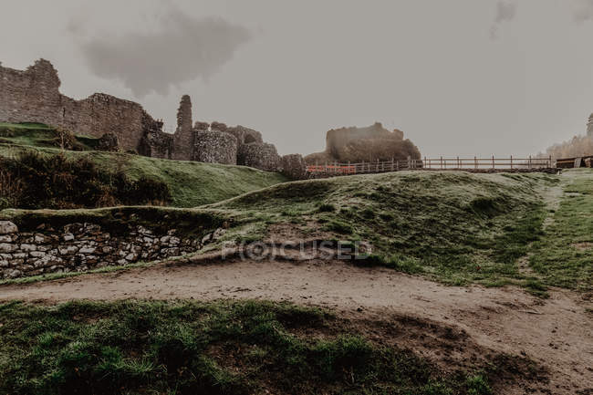 Castillo de piedra viejo destruido con niebla con paredes y escaleras con torre en día nublado - foto de stock