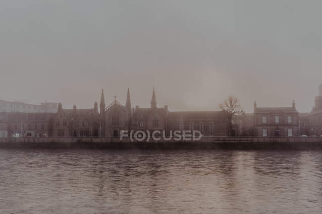 Річка і туманна вулиця зі старою архітектурою з кам'яними будівлями в похмурий день — стокове фото