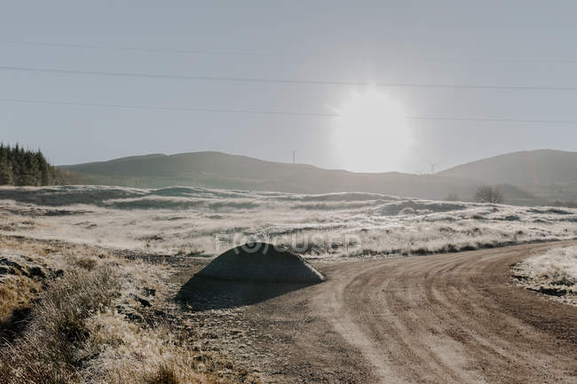 Strada innevata con svolta in campagna passando attraverso le montagne all'alba — Foto stock
