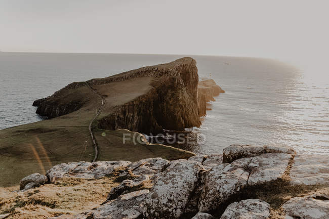 Klippen an der Küste und Leuchtturm in Meeresnähe gegen klaren blauen Himmel am sonnigen Tag, Insel des Himmels in Schottland — Stockfoto