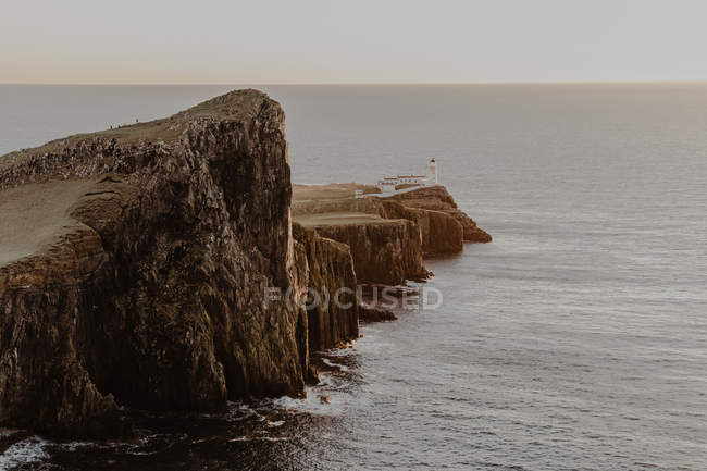 Coastal cliffs and Neist Point lighthouse near sea against clear blue sky on sunny daytime in Isle of Skye, Scotland — Stock Photo