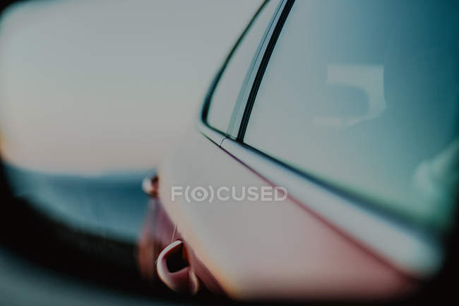 Red automobile reflected in rear view mirror during driving on road on sunny daytime — Stock Photo