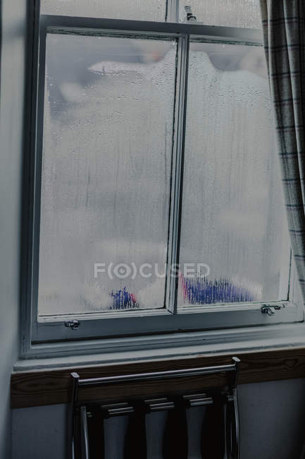 Großes vernebeltes Fenster im Zimmer und Stuhl in der Nähe, um die Winterlandschaft zu sehen — Stockfoto