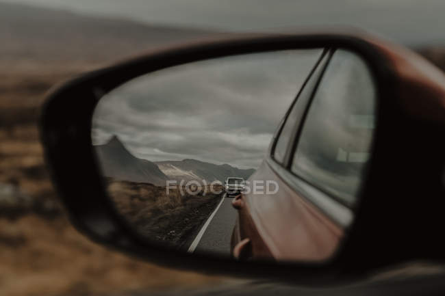 Reflexion des Autos auf der Straße vor dem Fenster auf der leeren Straße entlang trockenen hügeligen Tal in grauen Tag — Stockfoto