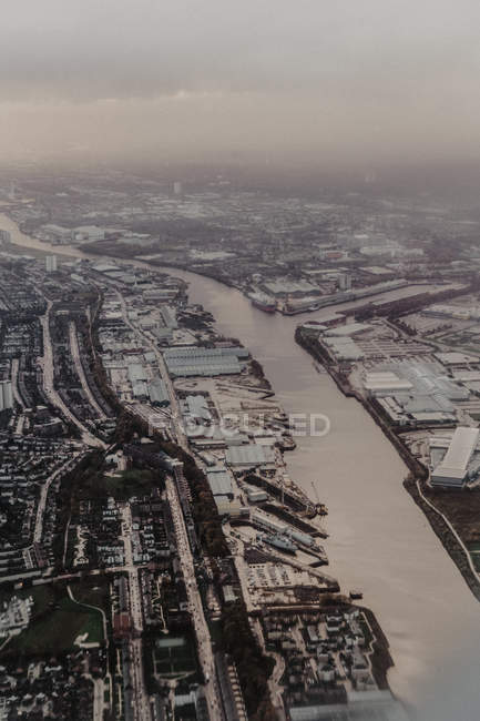 Dall'alto vista aerea della città densamente popolata con strade e case nascoste dietro nuvole bianche — Foto stock