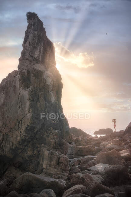 Roca en el mar contra acantilado verde - foto de stock