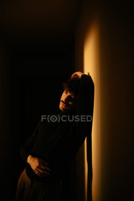 Людина з вусами сидить поруч зі стіною з піднятою рукою — стокове фото