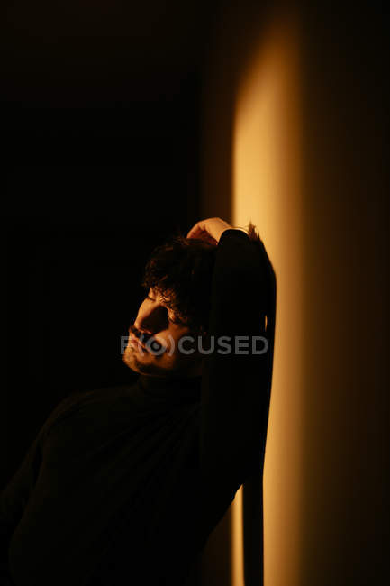 Junger trendiger Mann mit Schnurrbart sitzt mit erhobenem Arm über dem Kopf an der Wand — Stockfoto