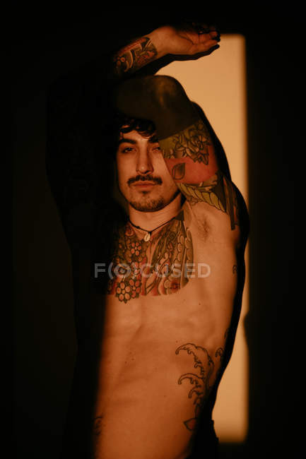 Bonito sem camisa tatuado homem posando sensualmente à luz do sol — Fotografia de Stock