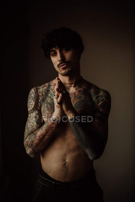 Красивый мужчина без рубашки с усами, пирсингом и татуировками, позирующий в студии — стоковое фото