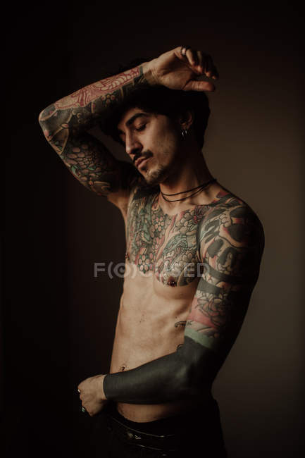 Bello uomo senza maglietta con baffi, piercing e tatuaggi in posa in studio — Foto stock