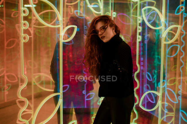 Schöne melancholische Brünette mit langen Haaren steht zwischen Leuchtreklamen an der Stadtstraße — Stockfoto