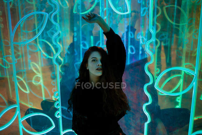 Stylische langhaarige Frau posiert zwischen Leuchtreklamen an der Stadtstraße — Stockfoto