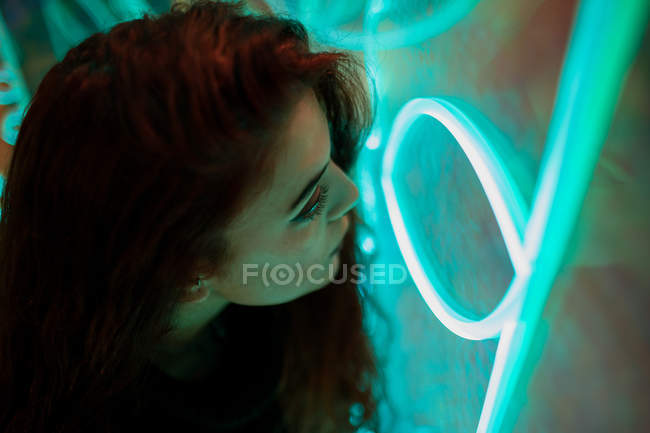 Stylish melancholic brunette neon signs leaning on wall at city street — Stock Photo
