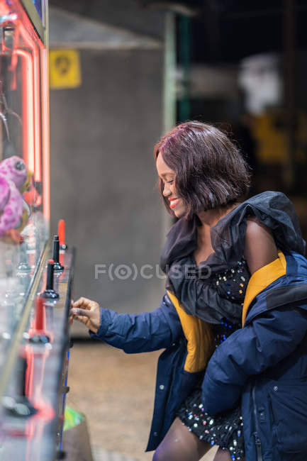 Black woman playing claw crane — Stock Photo