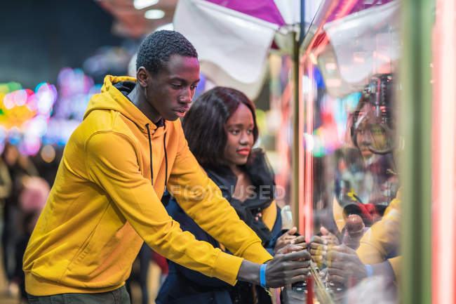 Black man playing claw crane for girlfriend — Stock Photo