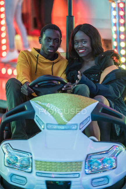Schwarzes Paar fährt Autoscooter auf Jahrmarkt — Stockfoto