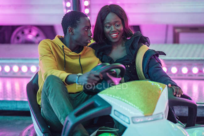 Black couple riding bumper car on funfair — Stock Photo