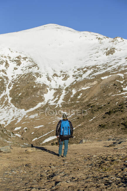 Traveler with backpack walking along dry valley in mountain — Stock Photo