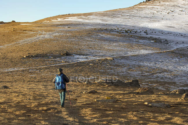 Viajero con mochila caminando por el valle seco en la montaña - foto de stock