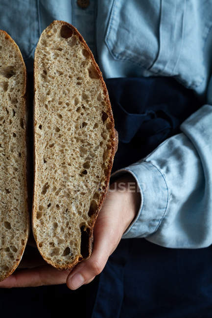 Hand of anonymous woman holding slices of homemade sourdough bread. — Stock Photo