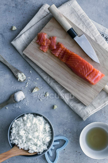 From above appetizing fresh sliced salmon and white tasty rice on table with wooden spoons and knife — Stock Photo