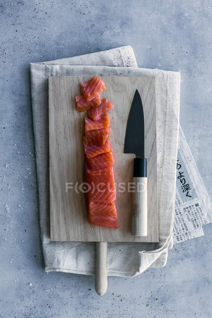 Зверху апетитний свіжий нарізаний лосось на столі з дерев'яною дошкою і ножем — стокове фото
