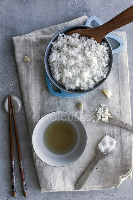 De acima mencionado saboroso arroz branco cozido fresco em tigela e vinagre em tigela servida na mesa com pauzinhos e condimentos — Fotografia de Stock