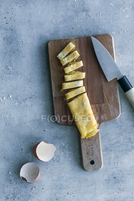 D'en haut omelette d'oeuf frais coupé savoureux avec coquille d'oeuf et couteau sur la table — Photo de stock