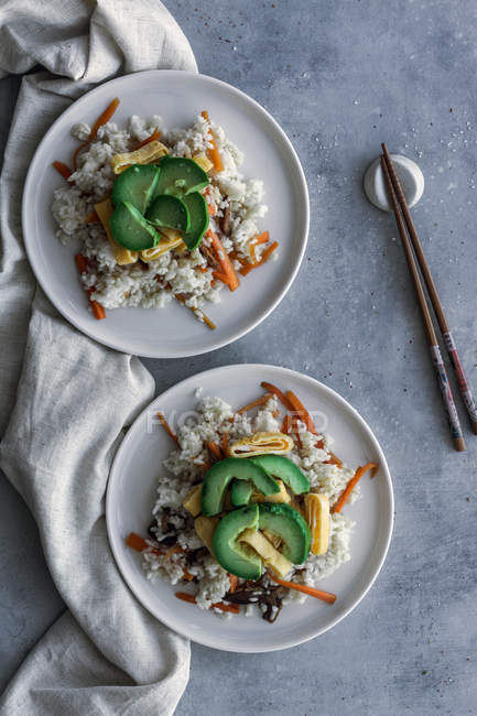 Зверху смачний апетитний білий рис з овочами в тарілках і паличками на столі — стокове фото