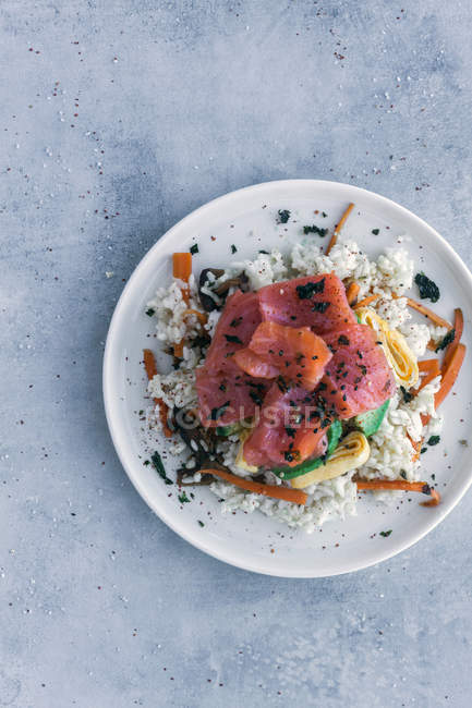 Dall'alto salmone affettato appetitoso saporito su riso bianco con verdure in piatto su tavolo con spazio di copia — Foto stock