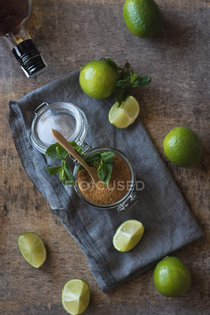 Накладні свіжі лапки і листя м'яти поміщають на серветку і стіл біля рому і коричневий цукор для приготування мохіто — стокове фото