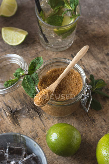 Limas frescas aéreas e folhas de hortelã-pimenta colocadas em guardanapo e mesa perto de rum e açúcar mascavo para preparação de mojito — Fotografia de Stock