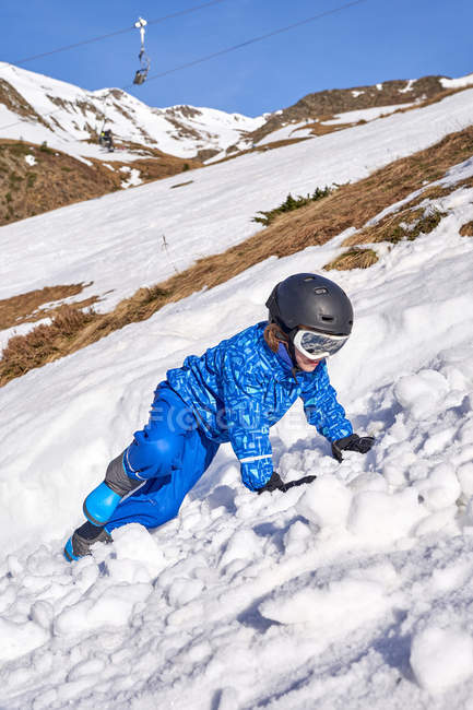 Menino bonito em terno de esqui azul, óculos e capacete na montanha nevada desfrutando e se divertindo — Fotografia de Stock