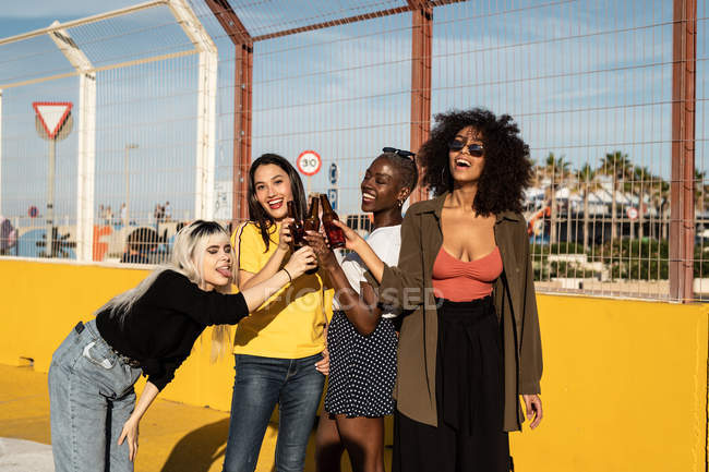Cheerful young diverse female friends celebrating meeting in city — Stock Photo
