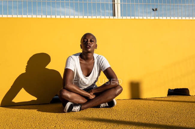 Confident young ethnic woman sitting on ground on stadium — Stock Photo