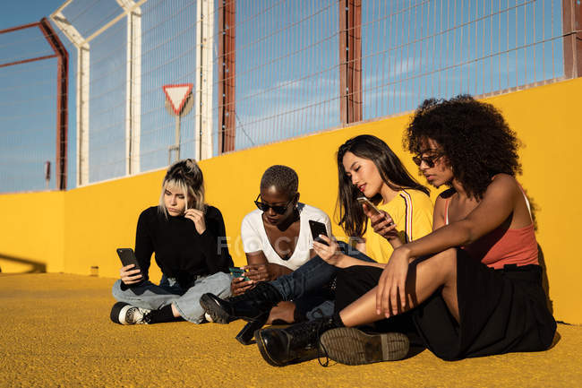 Беззаботные молодые многорасовые подруги используют смартфон на стадионе — стоковое фото
