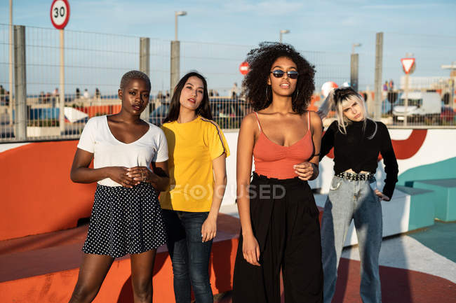 Confident young multiethnic female friends enjoying pastime in street — Stock Photo