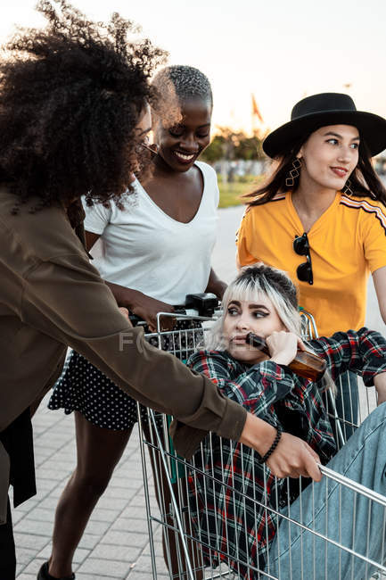 Grupo multirracial de mujeres jóvenes de pie alrededor del carrito de la compra en la carretera - foto de stock