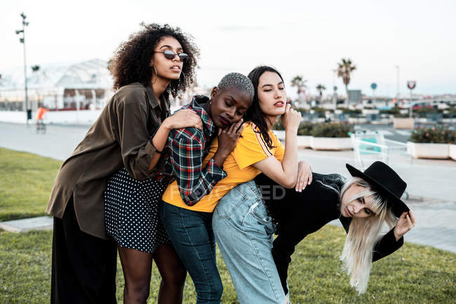 Grupo diverso de mulheres sorridentes abraçando juntas no gramado — Fotografia de Stock