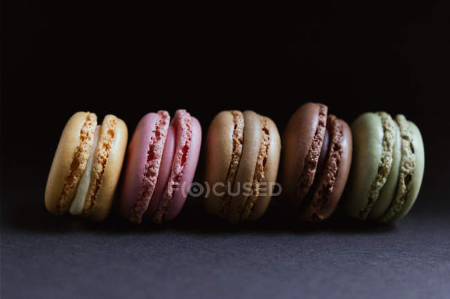 Fila di macaron croccanti freschi colorati su sfondo scuro — Foto stock