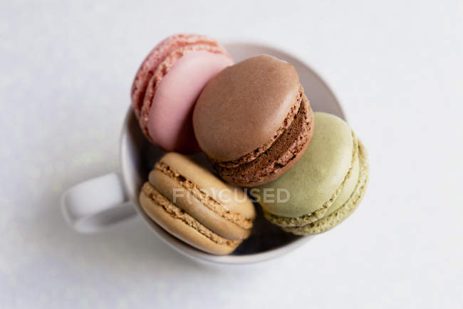 Top view of cup of tender colorful macaroons on white background — Stock Photo
