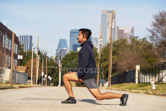 Un coureur hispanique en tenue active s'étire et se réchauffe avant la pratique dans le centre-ville de Dallas, USA — Photo de stock