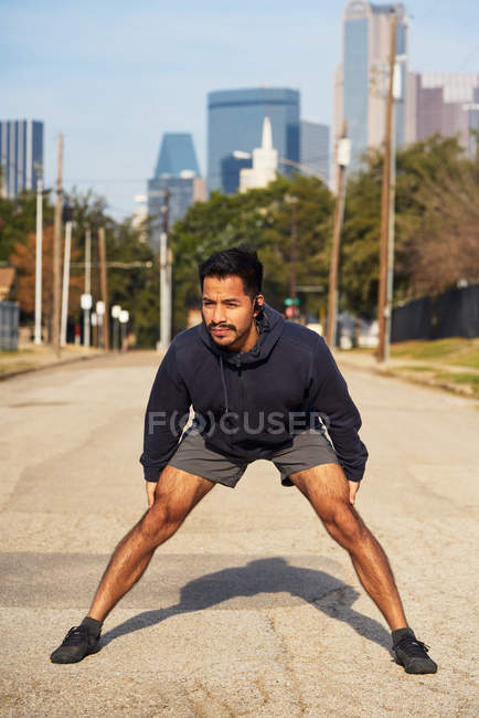 Hispanic male athlete in active wear standing and bending in downtown Dallas, USA — Stock Photo