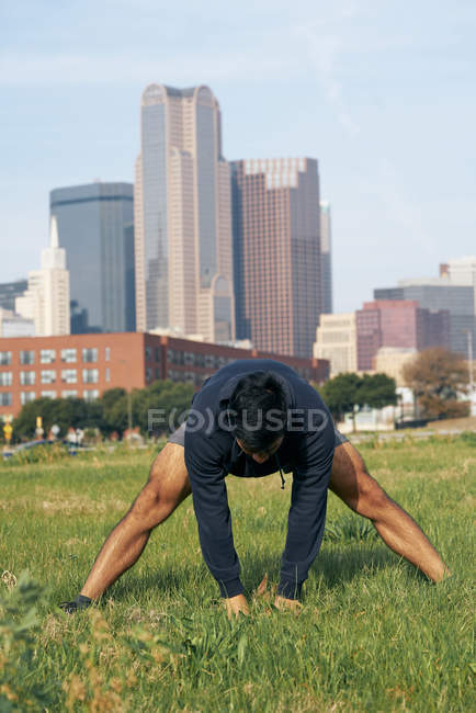 Fit Sportler in aktiver Kleidung Stretching im grünen Park in der Innenstadt von Dallas, Texas, USA — Stockfoto