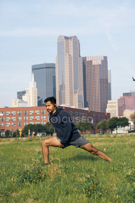 Ajuste deportista en desgaste activo haciendo embestida en parque verde en el centro de Dallas, Texas, EE.UU. - foto de stock